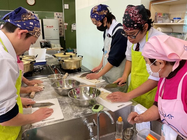 まな板に向かって食材を切る生徒たち