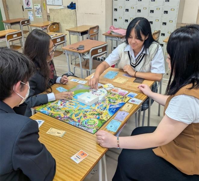 座って人生ゲームで遊んでいる様子