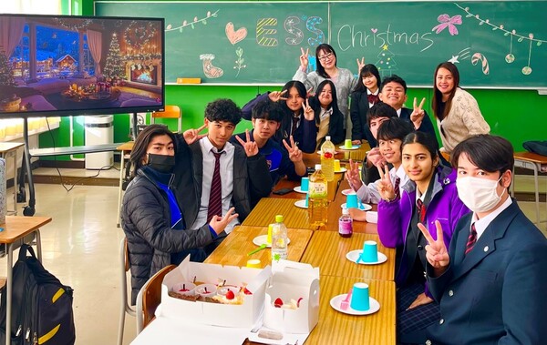 ケーキを食べる机を囲んでピースサインをする生徒たち