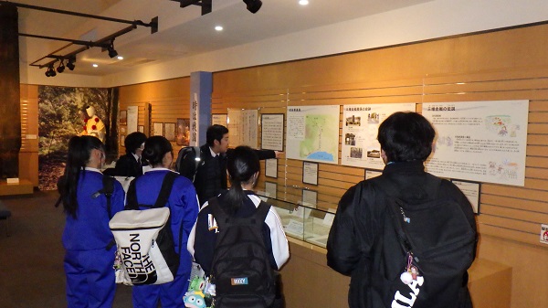 資料館の展示の説明を聞く生徒たち