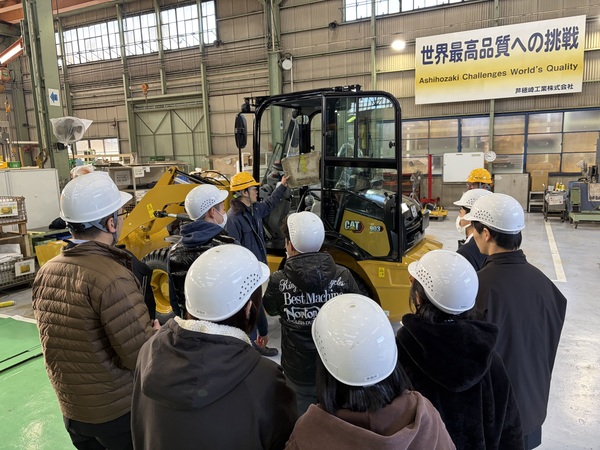 建物の中で建機の説明を受ける生徒たち